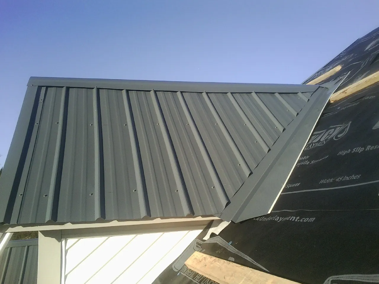 Gray metal roof panels going on over a garage gable in Smyrna