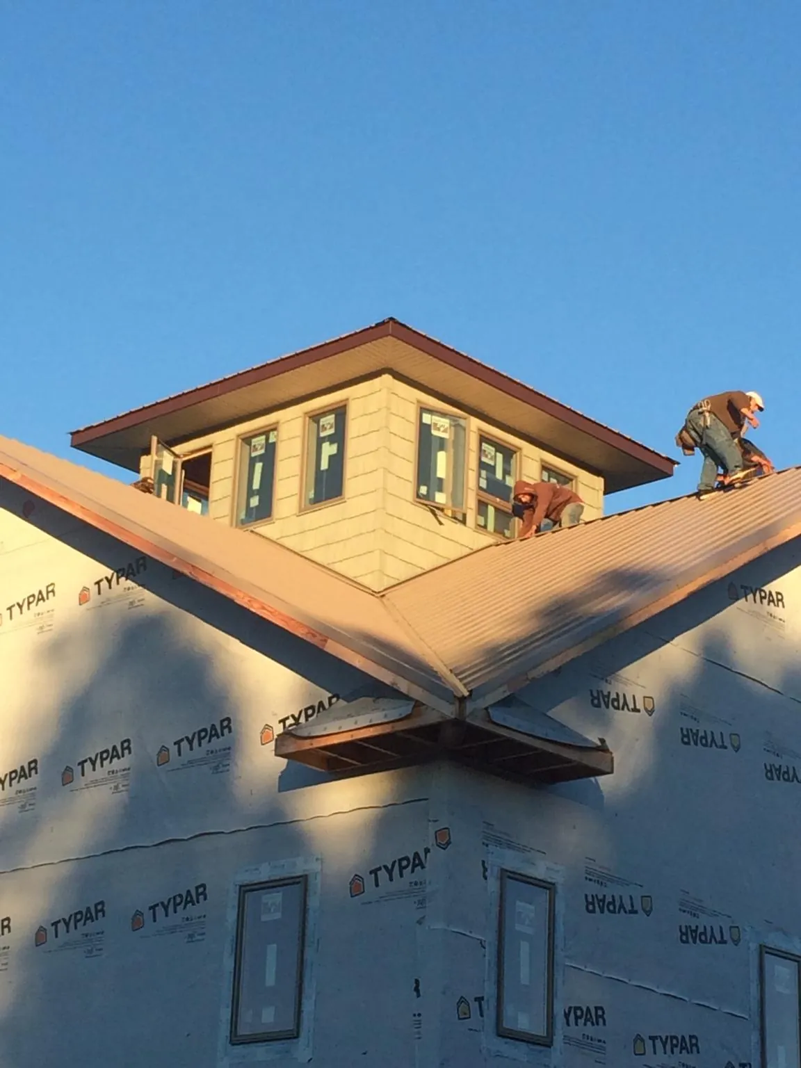 Roofers working around a rooftop cupola on a new metal roof at sunset — Roof Waterproofing in Smyrna by Roofing Brothers